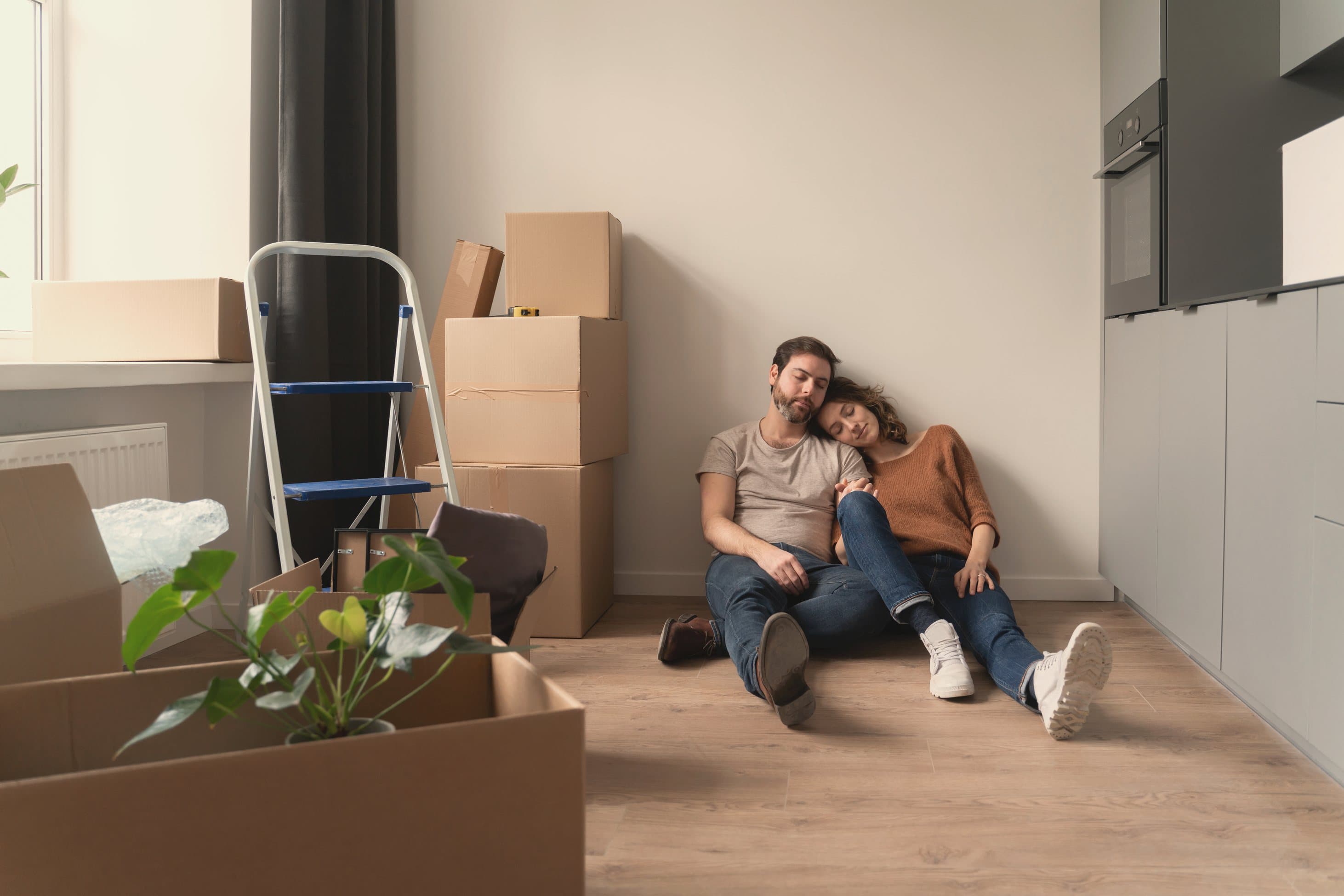 A couple resting among moving boxes in their new home