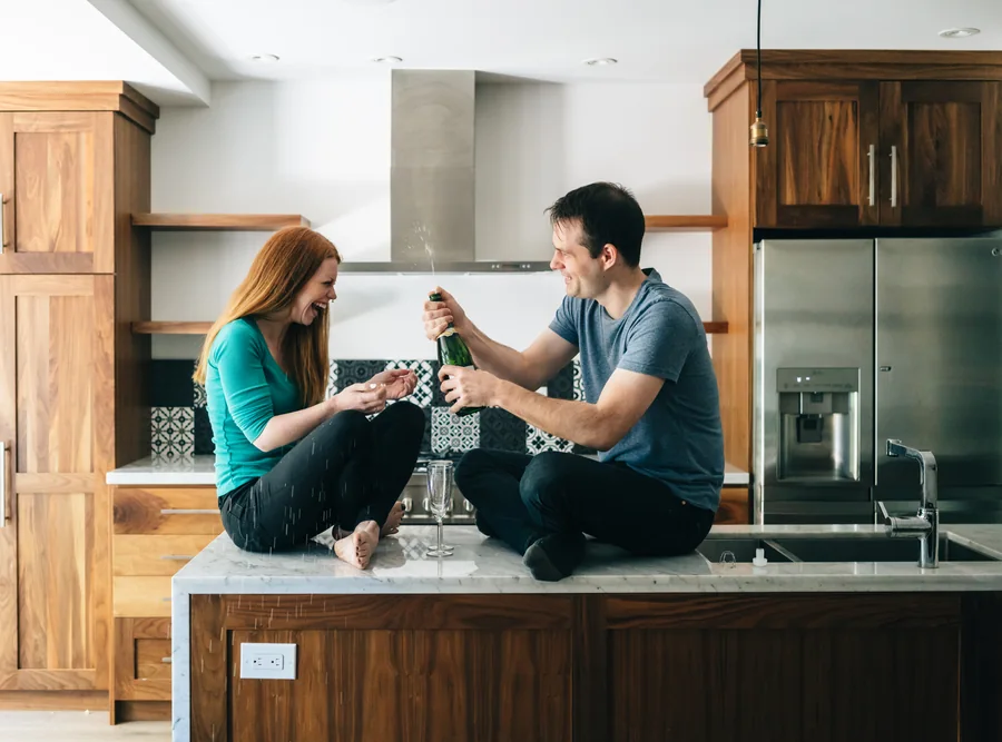 A couple celebrating in the kitchen of their first home